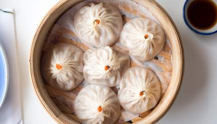 Xiao long bao steamed buns in a small bamboo basket