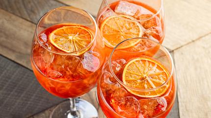 aperitif with ice and a slice of orange in large round glasses
