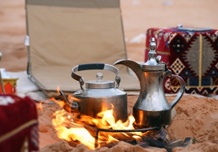 A dallah and a kettle over an open fire