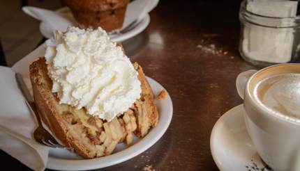 Äppelpaj (appeltaart) med vispad grädde på toppen och kaffe vid sidan