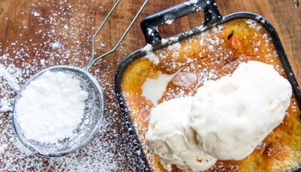 Malva pudding with vanilla ice cream on top and icing sugar on the side