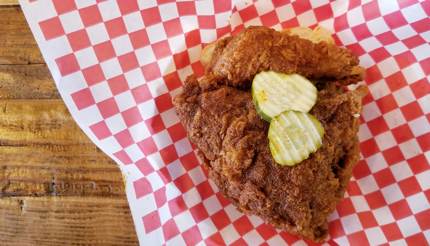 Hot chicken topped with gerkins on top of plain sliced bread